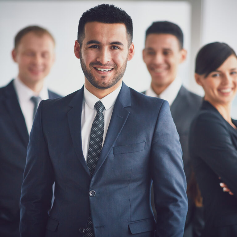Portrait of confident business partners looking at camera with smiling leader in front